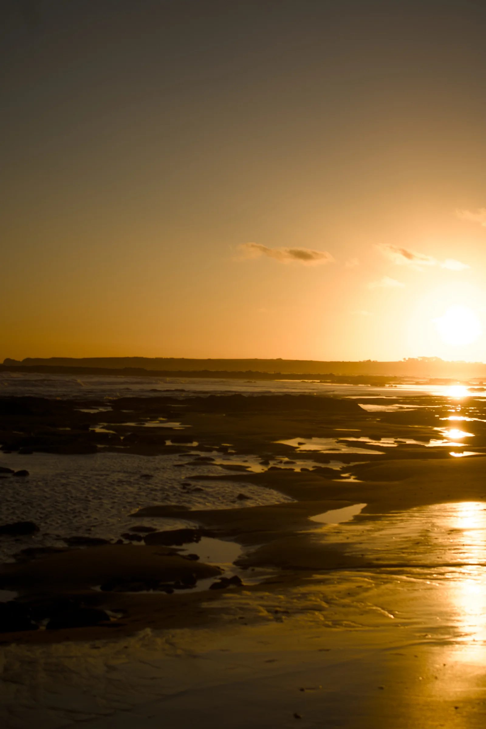 The sunset on the beach, reflected across the sand, water and rocks. Beautiful.