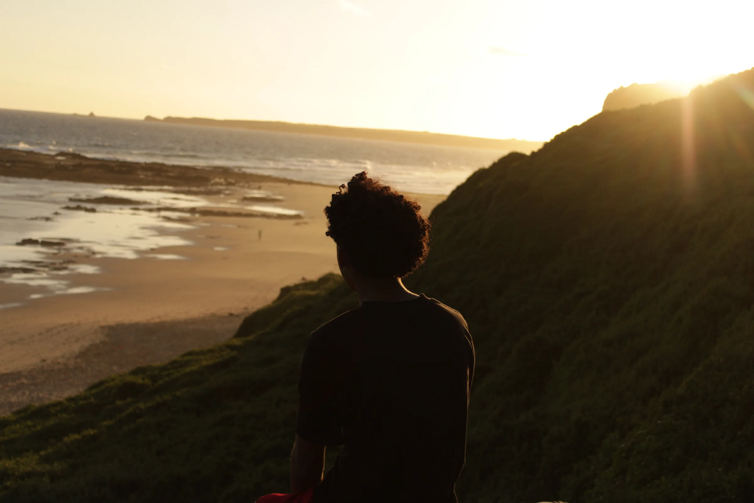 My mate (Tyrese), sitting on a seat, looking over the beach at sunset.