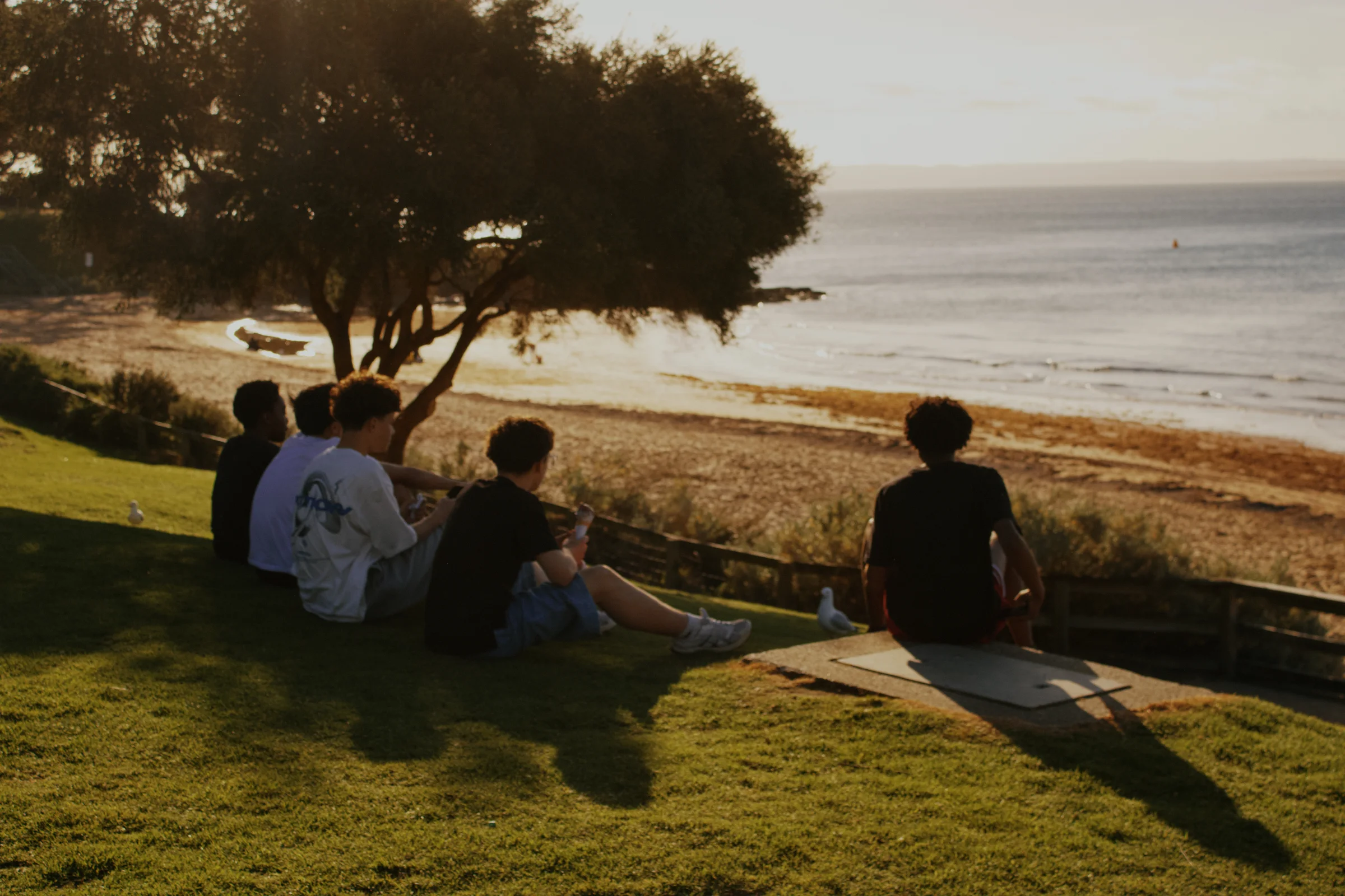 An image of 5 friends, watching the beach as they eat ice cream.