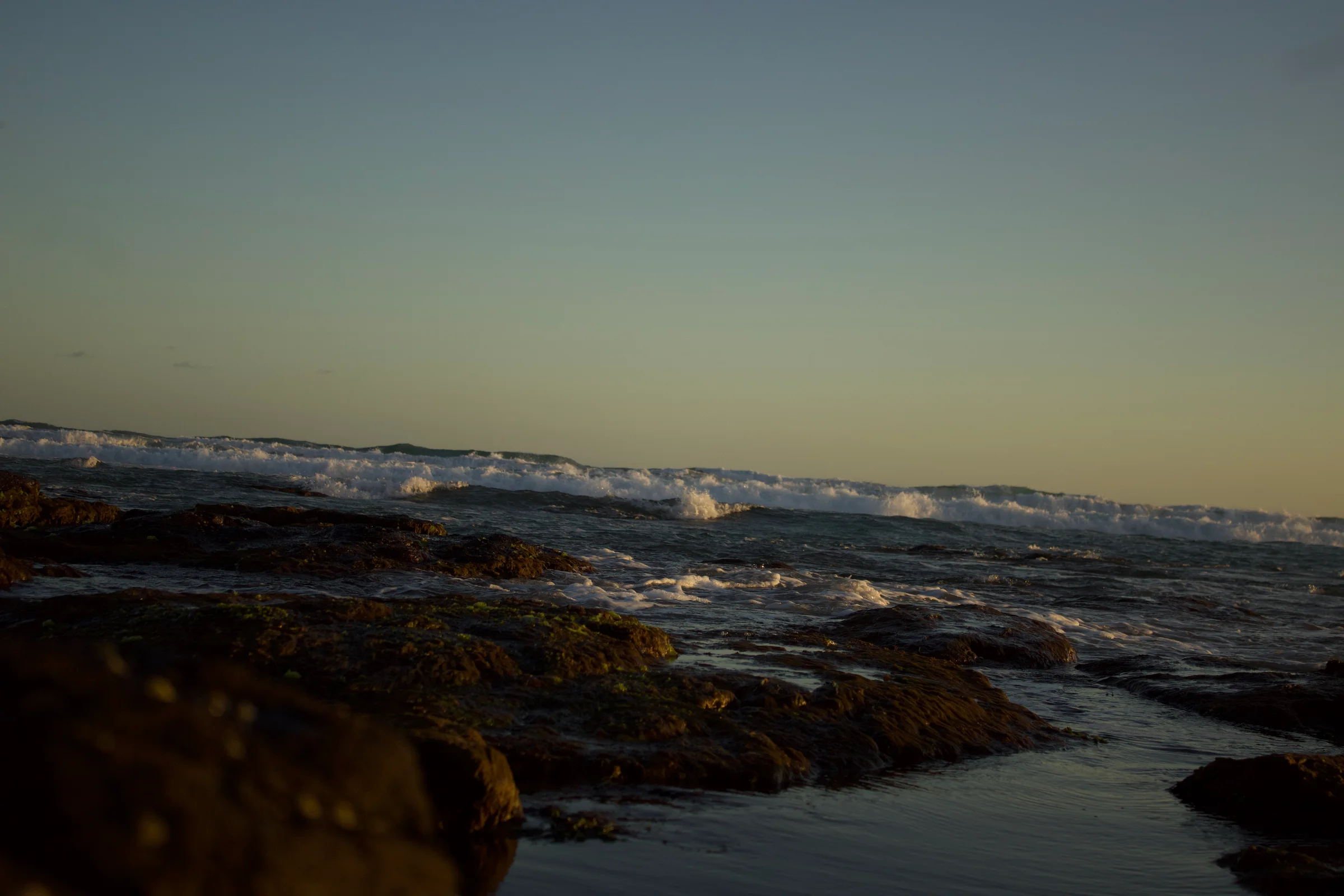 Waves rolling into the rocky shore of Phillip Island's beach.